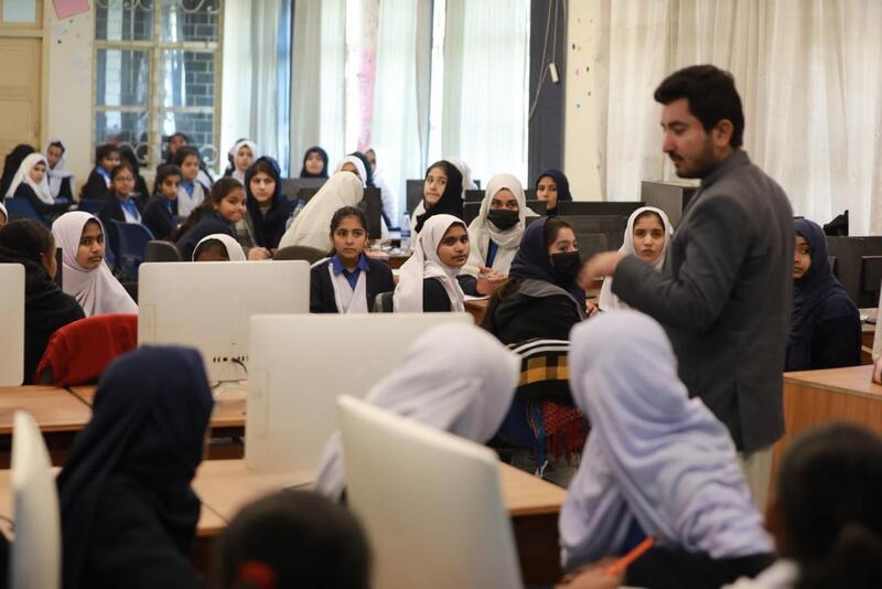 A group of students in a classroom listening to a speaker.